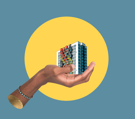 Building in hand ownership concept. African American male holding modern high rise apartment collage, showing real estate investment, urban architecture, residential property development and creativeの写真素材