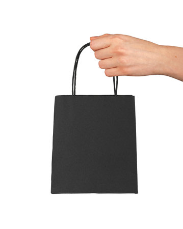 Hand holding small black paper bag, concept of shopping, beauty and luxury product purchase, minimal modern design symbolizing fashion retail and Black Friday sale isolated on white background.の写真素材