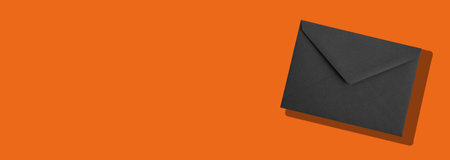 Black envelope on orange background with soft shadow, minimal elegant composition for business communication, branding or invitation concept, modern stylish design symbolizing contrast andの写真素材