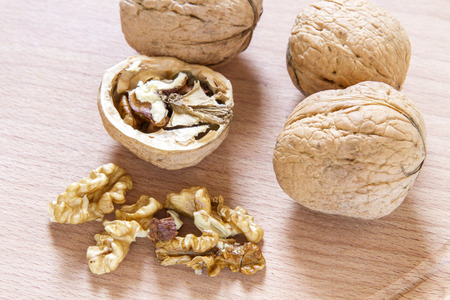 Walnut kernels and whole walnuts on rustic  wooden table .