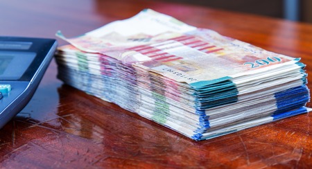 Israeli New Sheqel and calculator on wood background .の写真素材