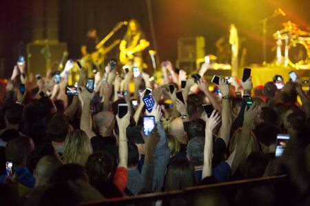 Crowd at concert and blurred stage lights . Close up of photographing with smartphone during a...
