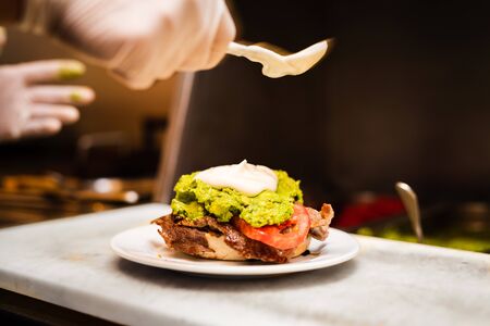 preparing sandiwch with meat, onion, mayo and picklesの写真素材