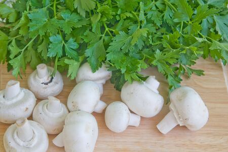 some mushrooms and parsley on kitchen boardの写真素材