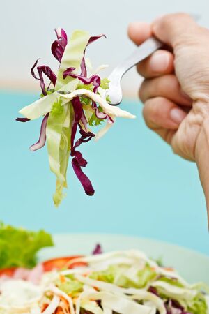 Hand holding fork and vegetables saladの写真素材