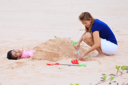 Asian mother and son playing on sand beachの写真素材