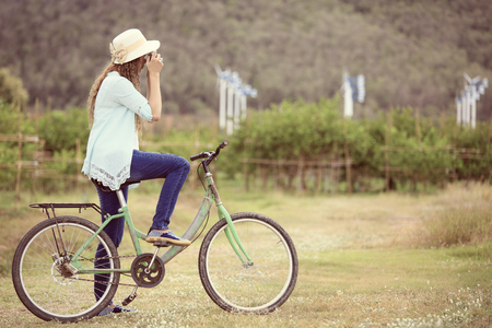 Woman on bicycle taking photo with wind turbine in backgroundの写真素材