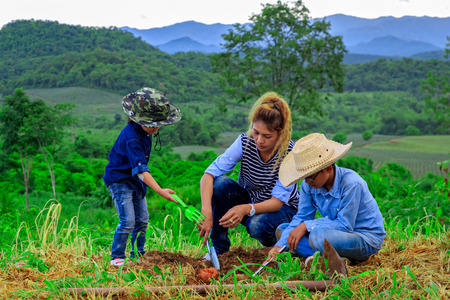 Asian family planting tree in farm near mountainの写真素材