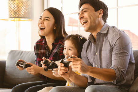 Diversity multiracial Caucasian and Asian family father, mother and daughter sitting together on...