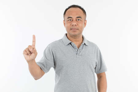 Portrait of middle age senior Asian man in a light grey cloth raising and showing one finger. Isolate on white background.の写真素材