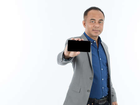 A self-confident senior Asian man in a blue business casual shirt with a grey jacket standing and...