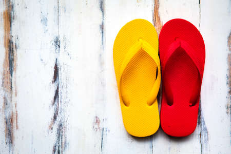 A pair of colorful red and yellow rubber slippers popular use on a sand beach and tropical tourist...