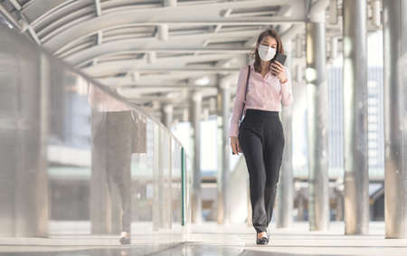 Beautiful adult middle age Asian working office businesswoman holding smartphone and talking while walking to office in big city. Idea for lifestyle of modern female worker in business hours.の写真素材