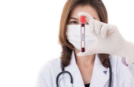Pretty beautiful Asian woman in doctor gown or lab coat wearing surgical hygiene mask holding and...
