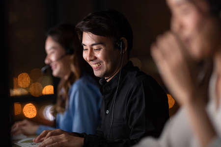 Young and beautiful call center officers team work overtime with happy at 24/7 hour at night with...
