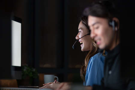 Young and beautiful call center officers team work overtime with happy at 24/7 hour at night with...