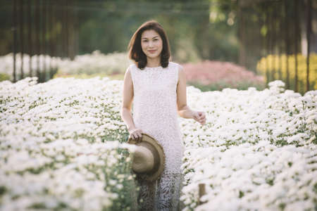 Beautiful Asian woman walking and smiling in tropical  flower garden with happiness manner with warm sunlight from background.の写真素材