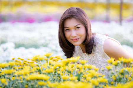 Beautiful Asian woman standing and smiling in tropical  flower garden with happiness manner with...
