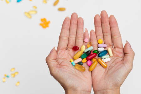 Assorted various kinds and many sizes of pills pharmaceutical in hands isolated on white background.