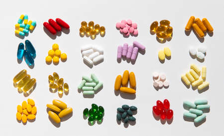 Group of assorted pharmaceutical medicine pills, colorful tablets and capsules with strong light and...