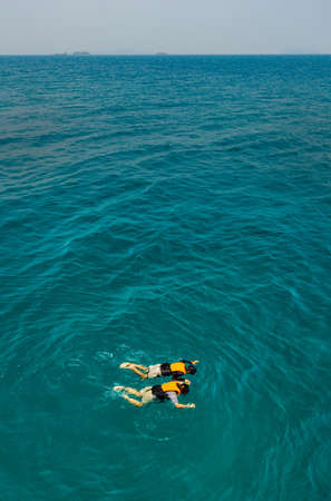 Two people man and woman catch each other hands and happy with nature and skin diving to see reefs and bottom of sea in clear water.の写真素材