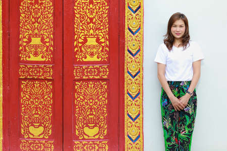 Asian woman in native Thai style pattern paint pants in with traditional Thailand Buddhist temple architecture.の写真素材