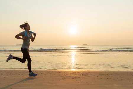 Asain good shape woman running on beach in the morning sunrise. Concept for good health and heathcare of modern people.の写真素材