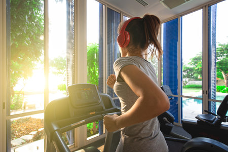 Good shape woman running on treadmill in indoor gym in morning light. Concept for healthcare of modern people.の写真素材