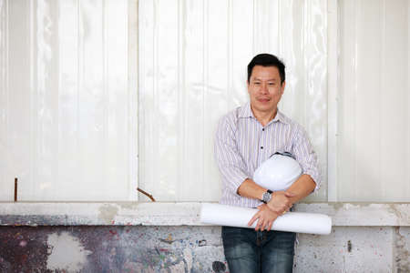 Portrait of male engineer with self-confidense and friendly manner, holding roll paperの写真素材