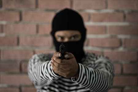 Robber aiming gun and looking in ready to shot manner