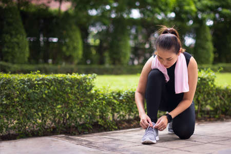 Young woman tying shoelaces before jogging in the park.の写真素材
