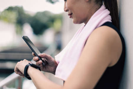 Adult mature women in sportswear compare, sync or reading results of fitness application on screen of smartphone and smartwatch devices after workout or exercise. Concept of good health care.の写真素材