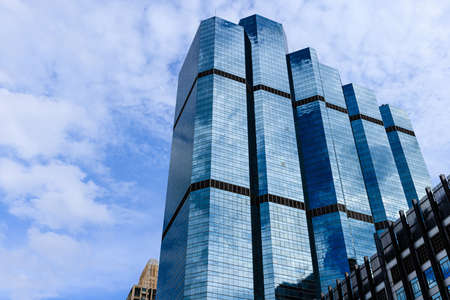 Blue sky and clouds reflected on the glass of office business buildings in the city center on a bright sunny day.の写真素材