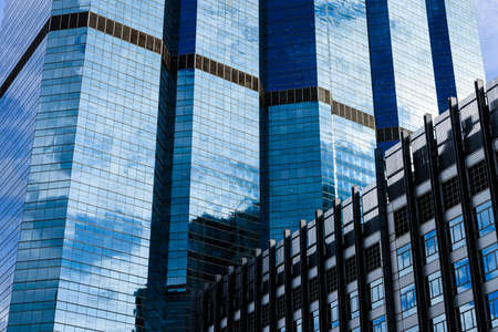 Blue sky and clouds reflected on the glass of office business buildings in the city center on a bright sunny day.の写真素材