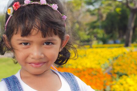 Little asian girl smile with shallow focus on flowers background