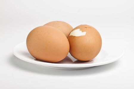 Three boiled eggs on white plate on white background