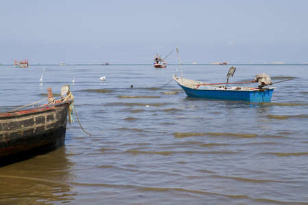 Fishing boat anchored on beach with blue sky background の写真素材