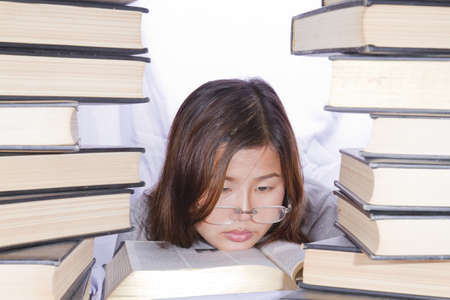 Asian girl in pile of books on white background