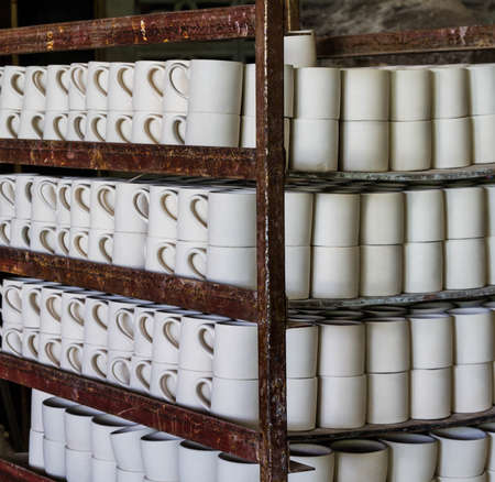 Stack of ceramic mugs in rackの写真素材