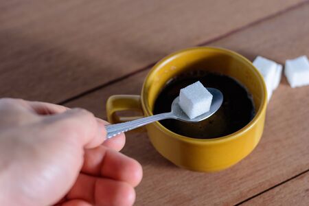 The hand is filling the sugar into the coffee.の写真素材