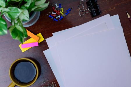 Coffee, file, pencil and office supplies. Placed beside a tree on a wooden table.