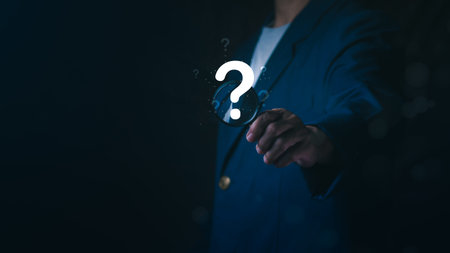 Businessman holding magnifying glass with glowing question mark icon, Concept of searching for answers, problem solving, market research, finding solutions, investigation, and business discovery.の写真素材