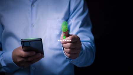 A businessman uses a green holographic fingerprint scanner for biometric authentication and secure login on a smartphone, Concept of cybersecurity, data protection, and advanced digital privacyの写真素材