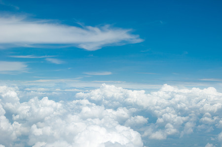 fluffy white clouds and blue sky background seen from airplaneの写真素材