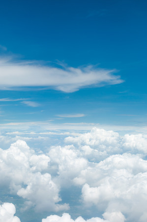 fluffy white clouds and blue sky background seen from airplaneの写真素材