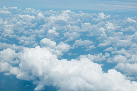 fluffy white clouds and blue sky background seen from airplaneの写真素材