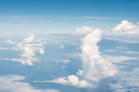 fluffy white clouds and blue sky background seen from airplaneの写真素材