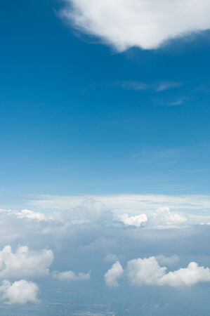 fluffy white clouds and blue sky background seen from airplaneの写真素材