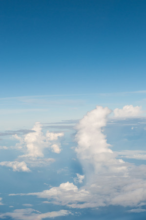 fluffy white clouds and blue sky background seen from airplaneの写真素材