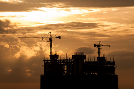 silhouette of crane and building construction on sunset